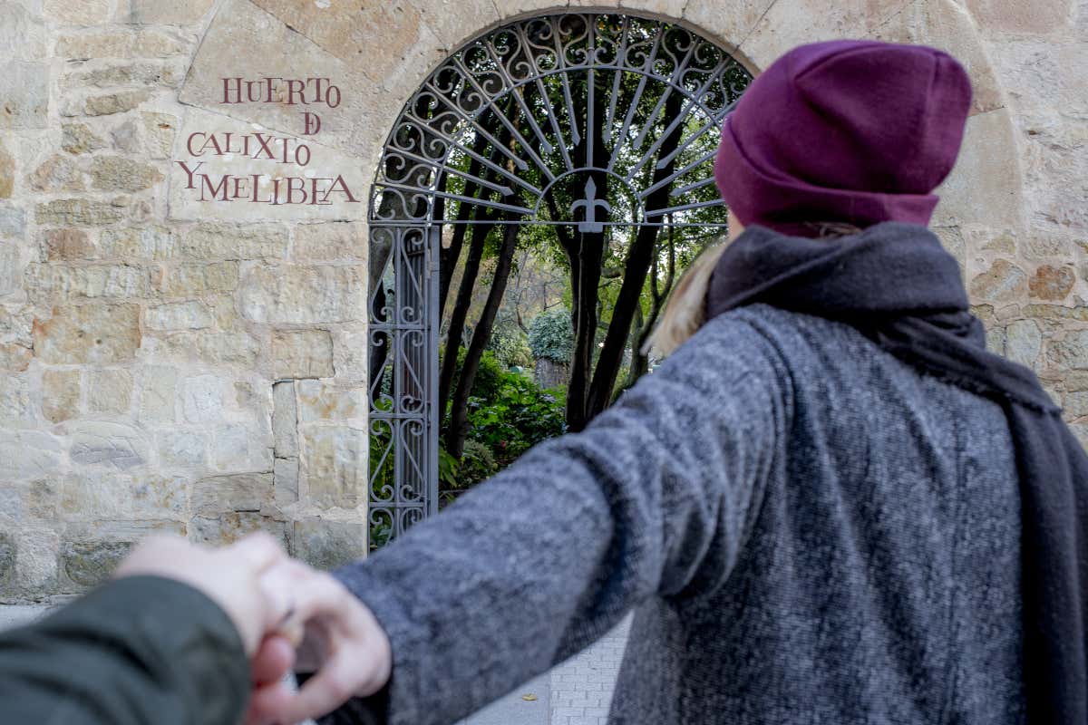 Una chica coge la mano de otra persona en la entrada del huerto de Calixto y Melibea de Salamanca