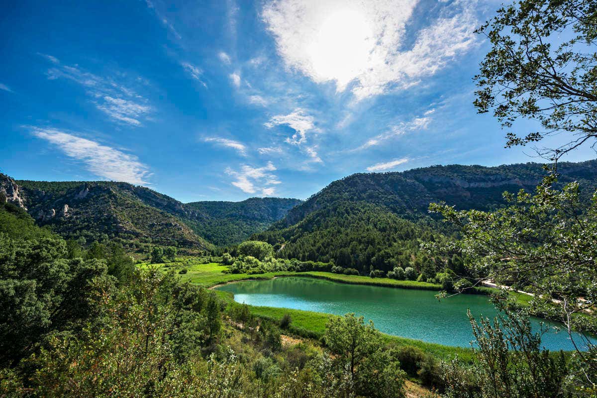 Paisaje de una laguna en medio de pequeñas montañas verdes