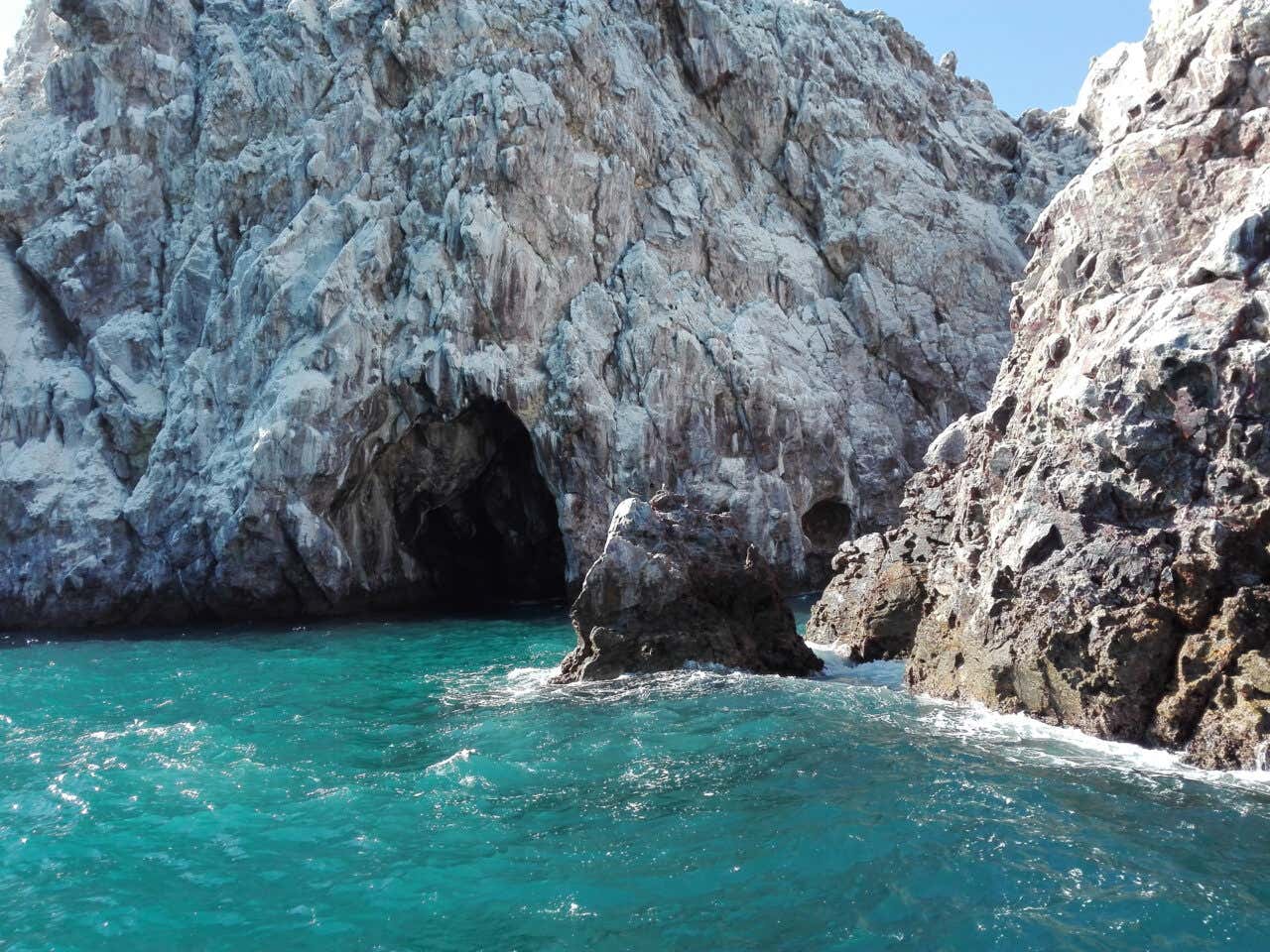 Isla de Piedra, or 'Stone Island' seen from off the coast, with bright blue water gently splashing below the rocks.