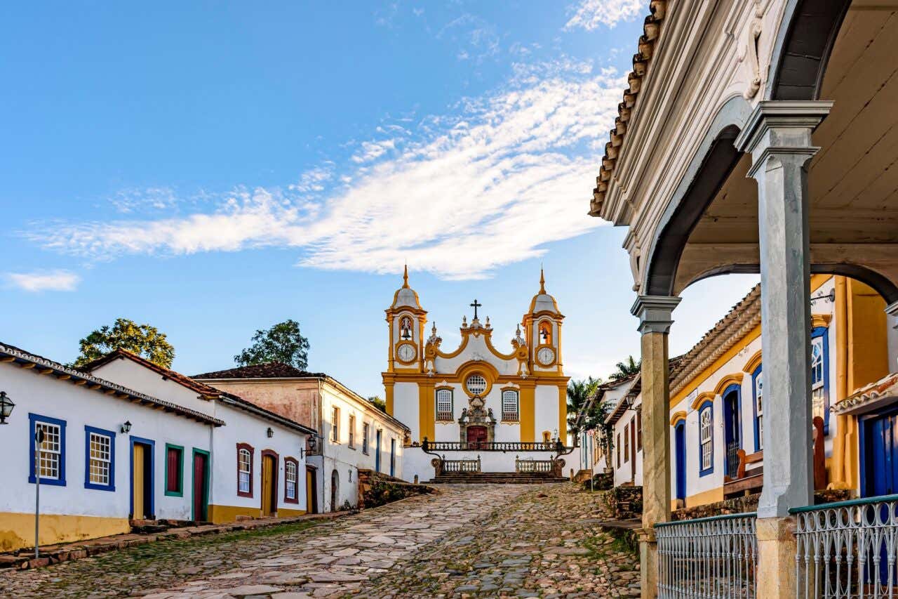 Uma rua histórica tranquila na cidade de Tiradentes, em Minas Gerais, com casas coloniais e uma igreja barroca ao fundo