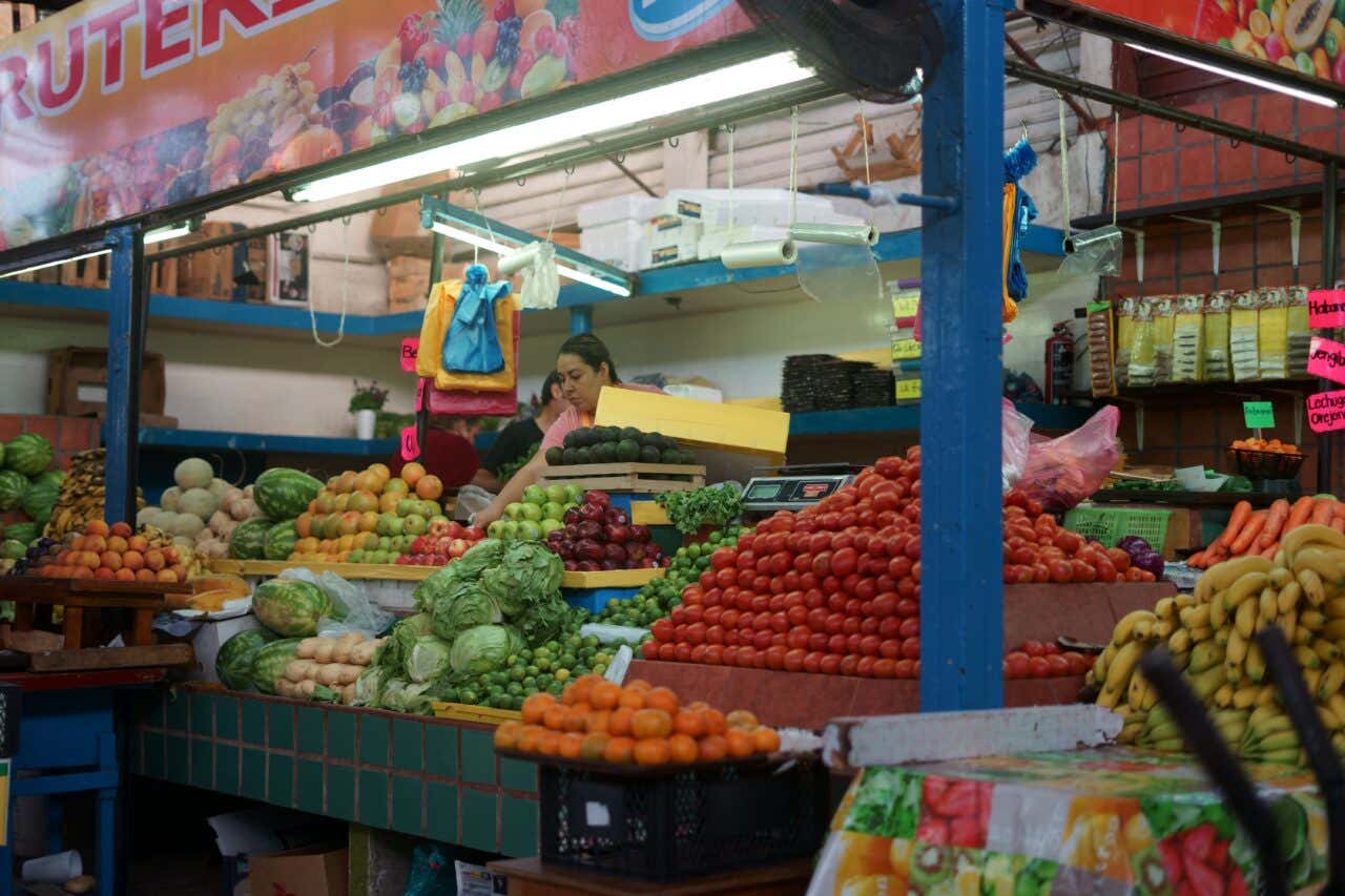 The fruit and vegetable stand at José María Pino Suarez Market, manned by a woman behind the produce.