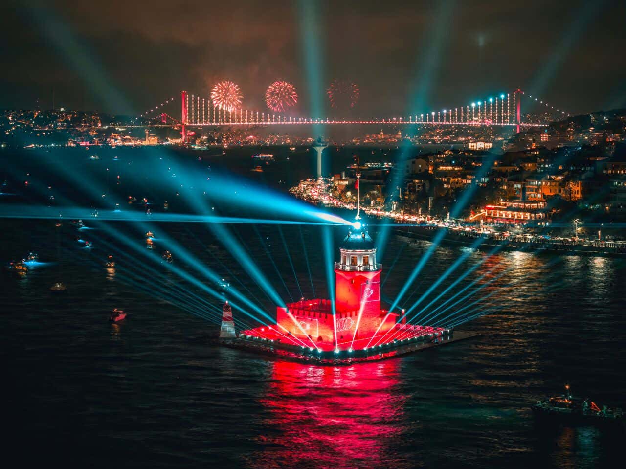 Celebrazioni di Capodanno a Istanbul con spettacolo di luci sul Bosforo, Ponte sul Bosforo illuminato in rosso e fuochi d'artificio sullo sfondo, vista notturna