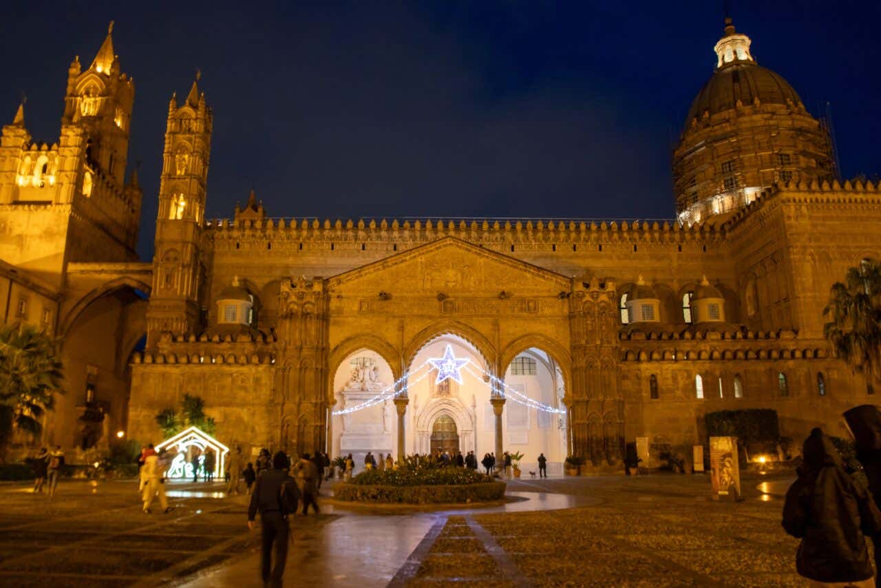 La cattedrale romanica di Palermo fotografata di notte a Natale. Il frontone dell'ingresso è diviso in tre arcate e decorato con luminarie natalizie