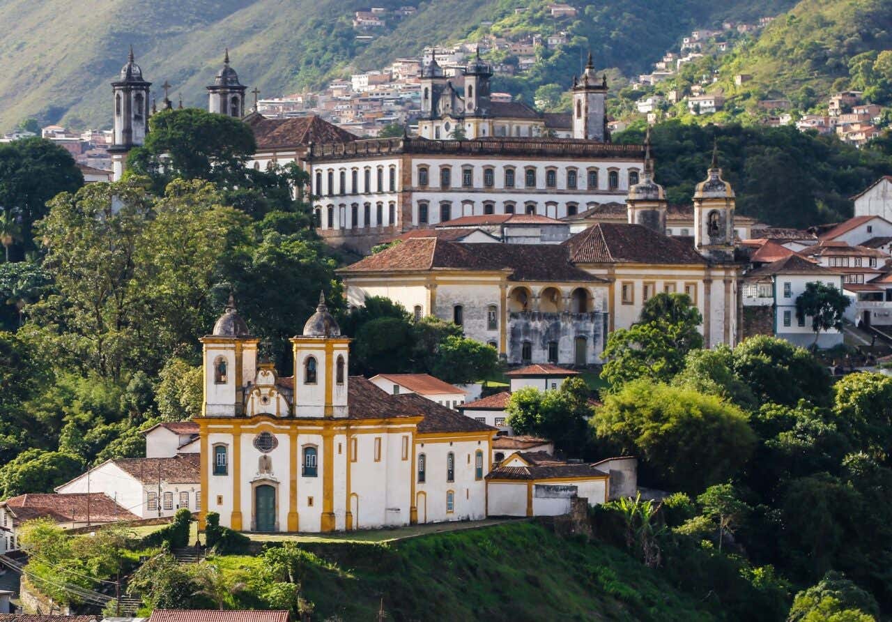 Panorâmica do centro histórico de Ouro Preto com casarões coloniais, igrejas barrocas e vegetação ao redor