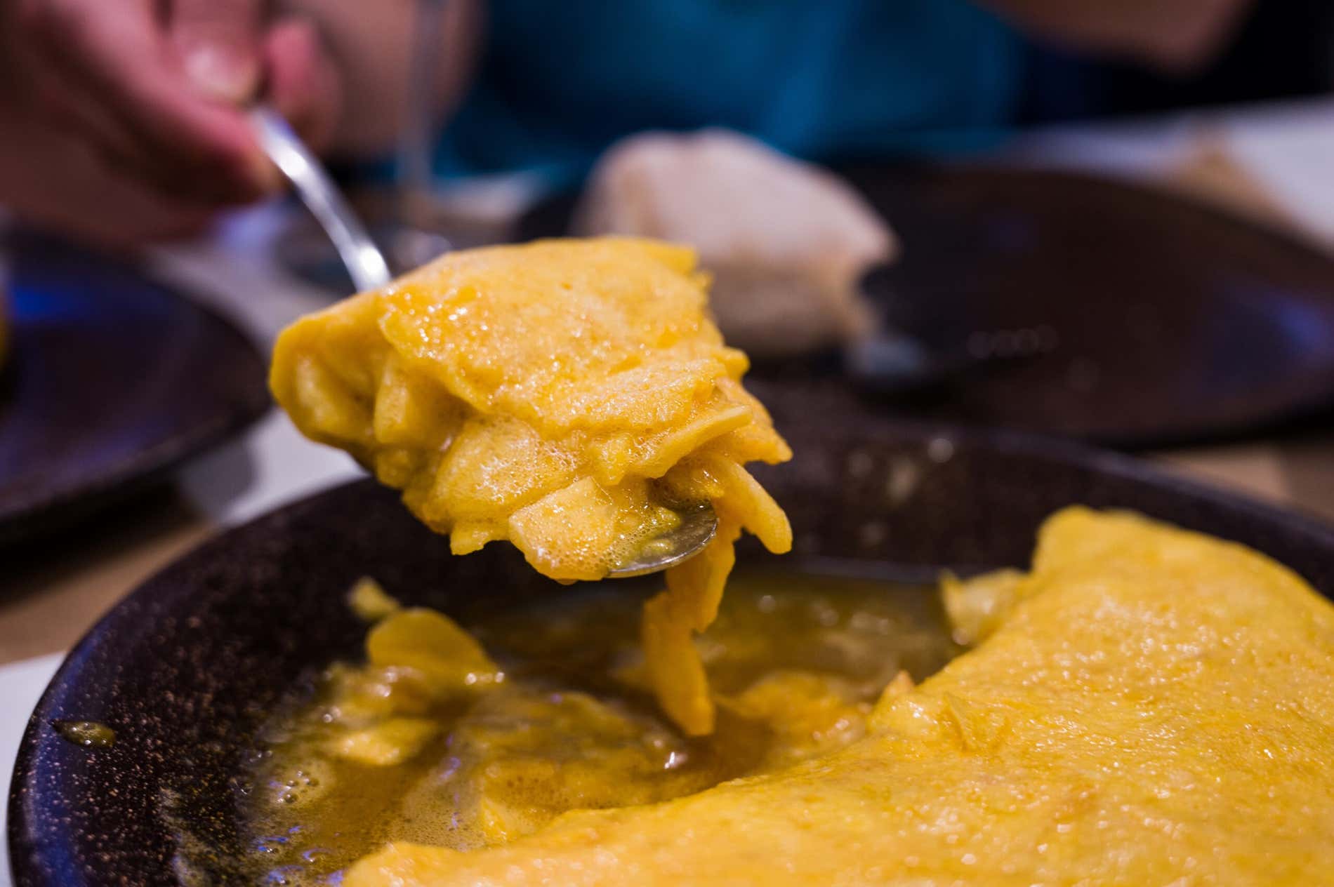 Detalhe de um garfo com um pedaço da omelete de batatas