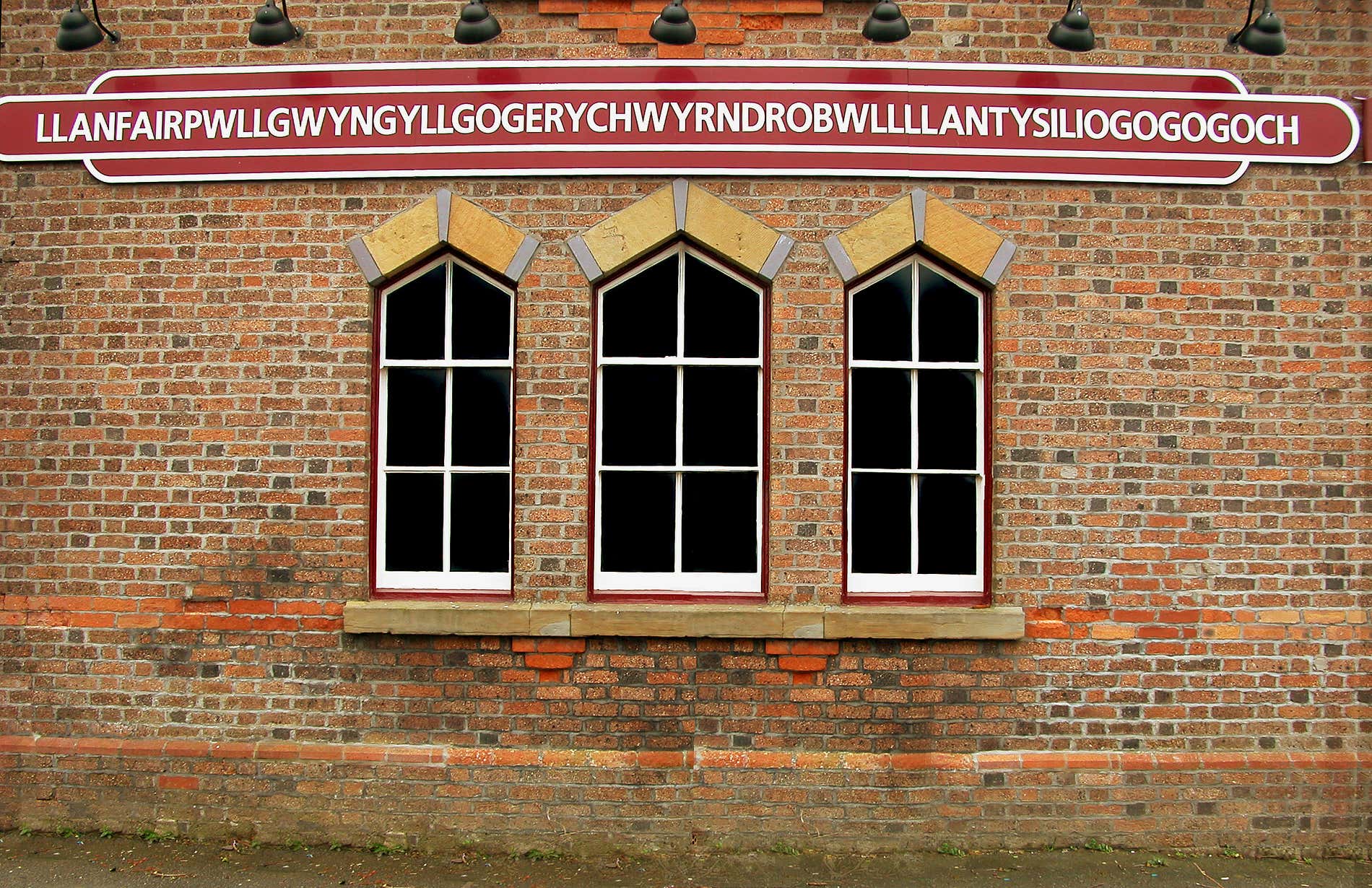 Edificio in una stazione ferroviaria con un cartello e una parola molto lunga in Gallese.