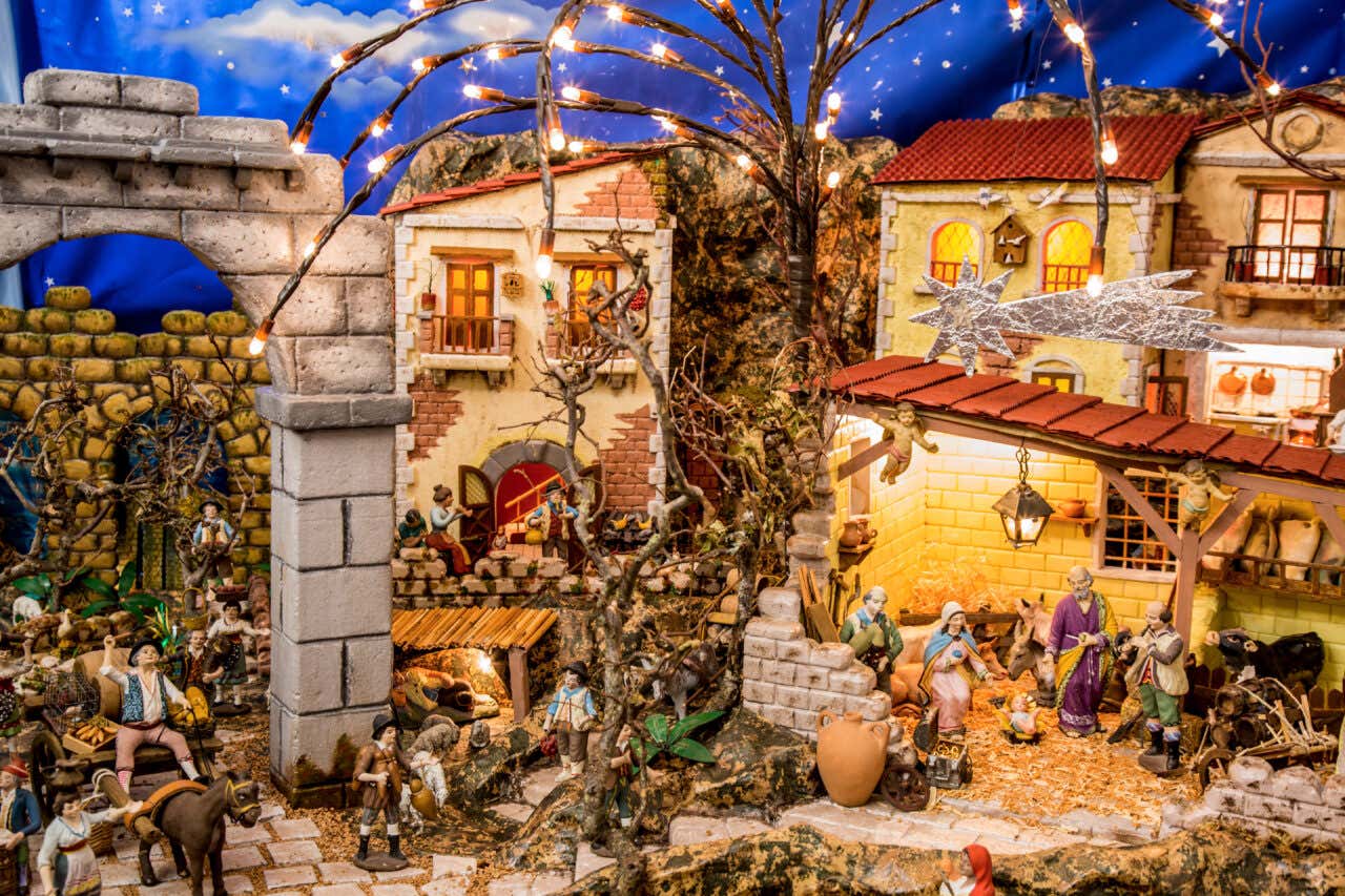 Un presepe con casette e ponti e disseminato di statuine rappresentanti contadini e persone comuni, mentre a destra c'è la raffigurazione della Natività