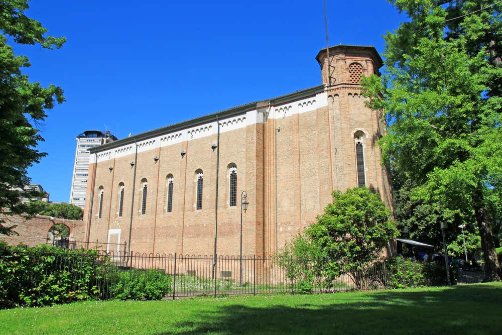 Una chiesa dalle alte mura e dall'aspetto gotico immersa nel verde di un giardino in una giornata di sole senza nuvole