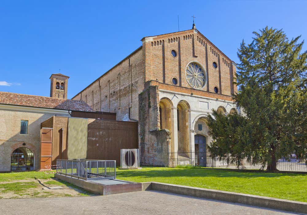 Facciata in mattoni della Chiesa degli Eremitani a Padova: portale centrale incorniciato da una loggia con archi su colonne, al di sopra un grande rosone circolare, e piccole aperture tonde; il frontone è semplice e triangolare, con dettagli architettonici sobri