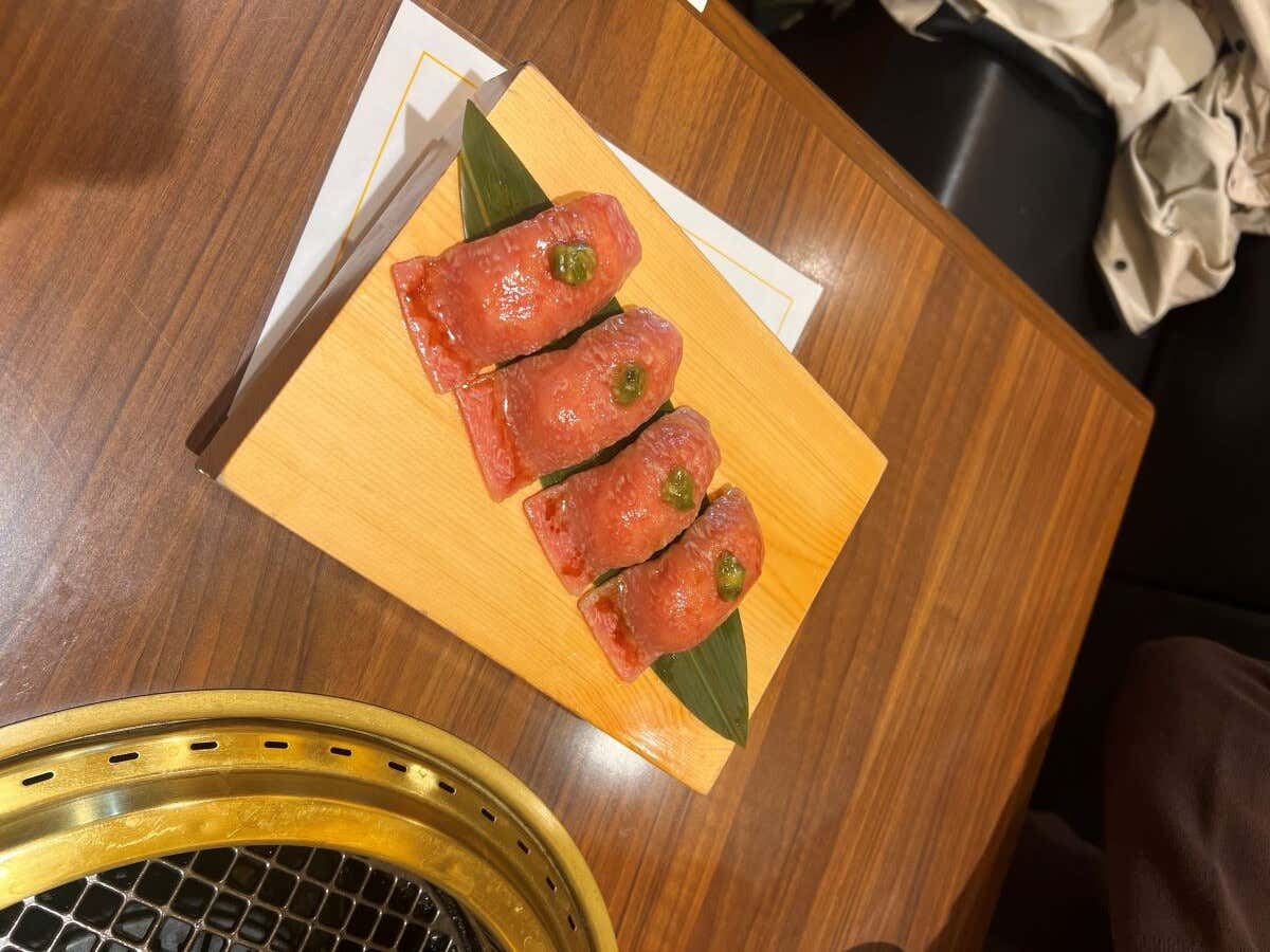 Cuatro piezas de sushi de wagyu sobre una tabla de madera