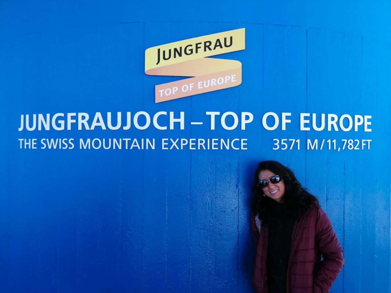 Una mujer sonríe en el letrero de Jungfraujoch