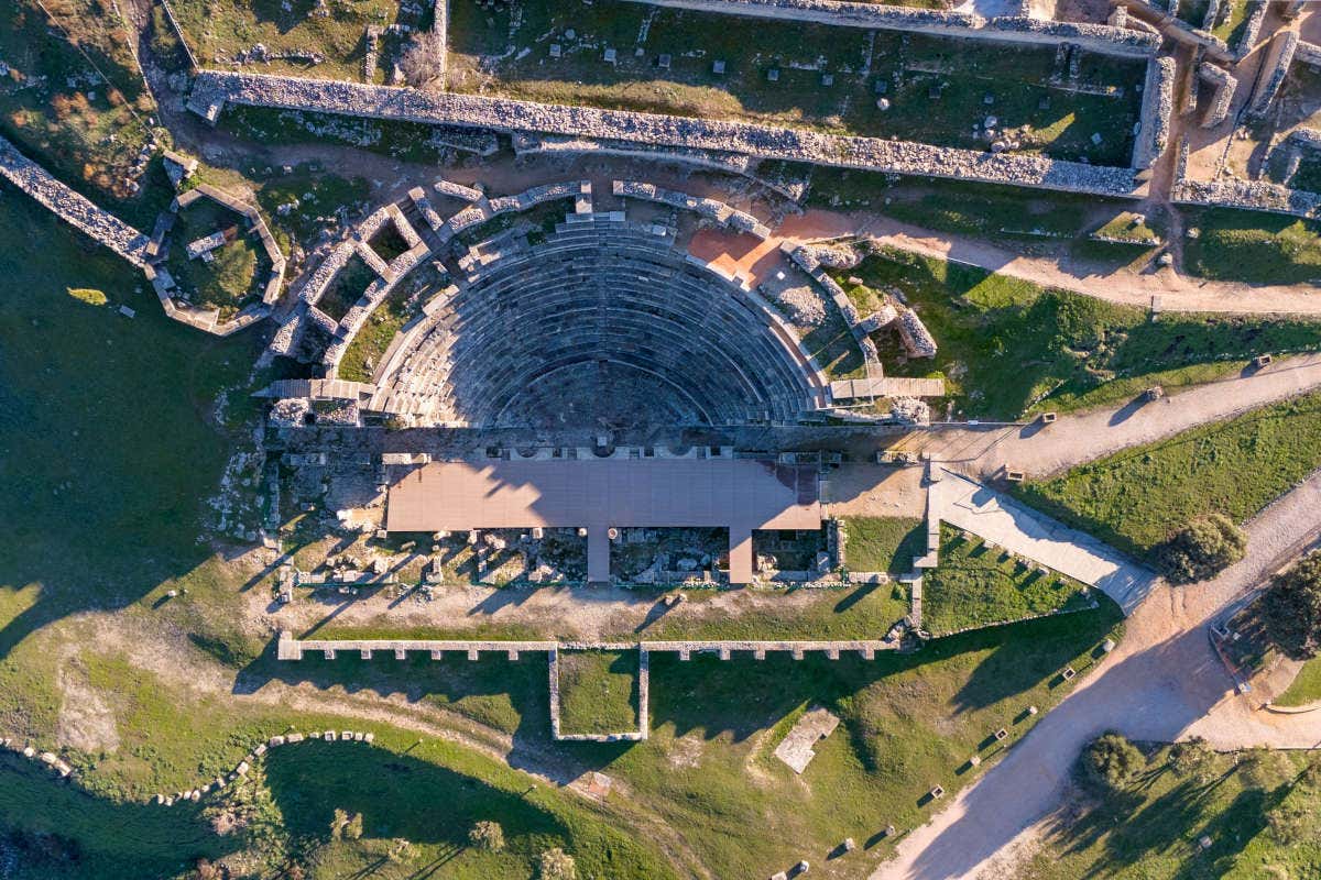 Vistas aéreas de un anfiteatro romano rodeados de jardines en un día soleado