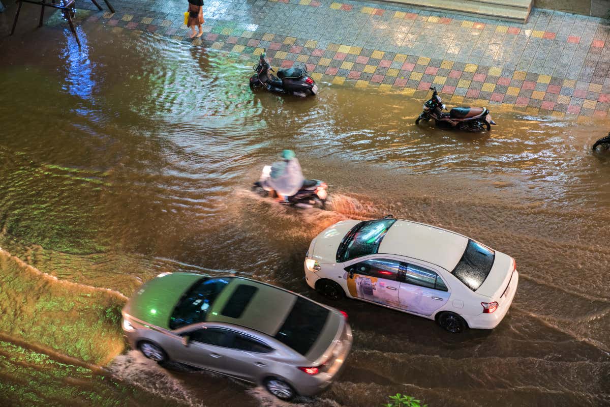 Rue d'Hanoï sous la pluie, avec des motos et deux voitures