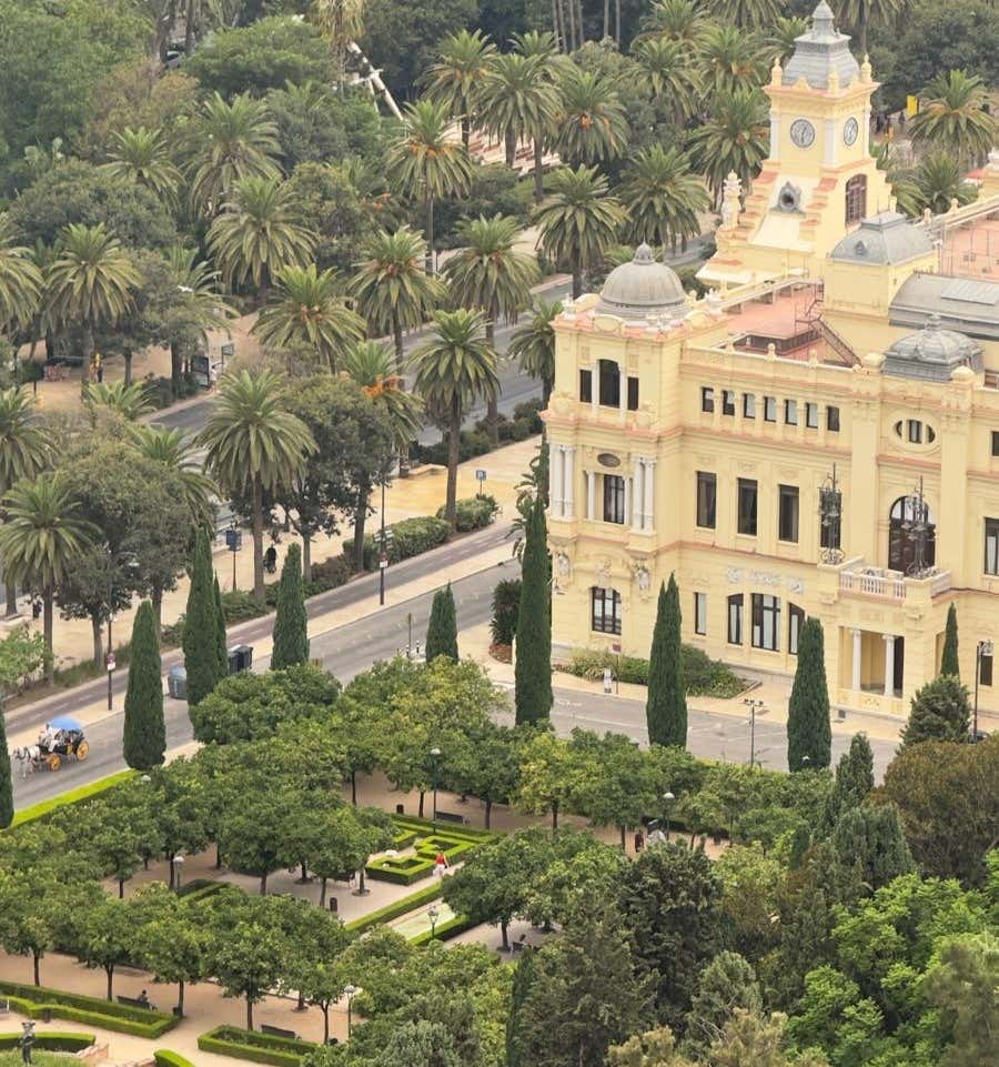 Views of the Málaga Park lined with palm trees and a historic building