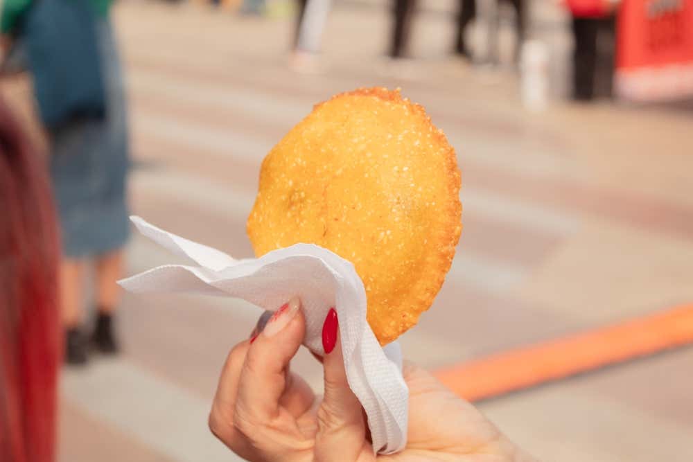 Plano detalle de la mano de una mujer sujetando una arepa de huevo