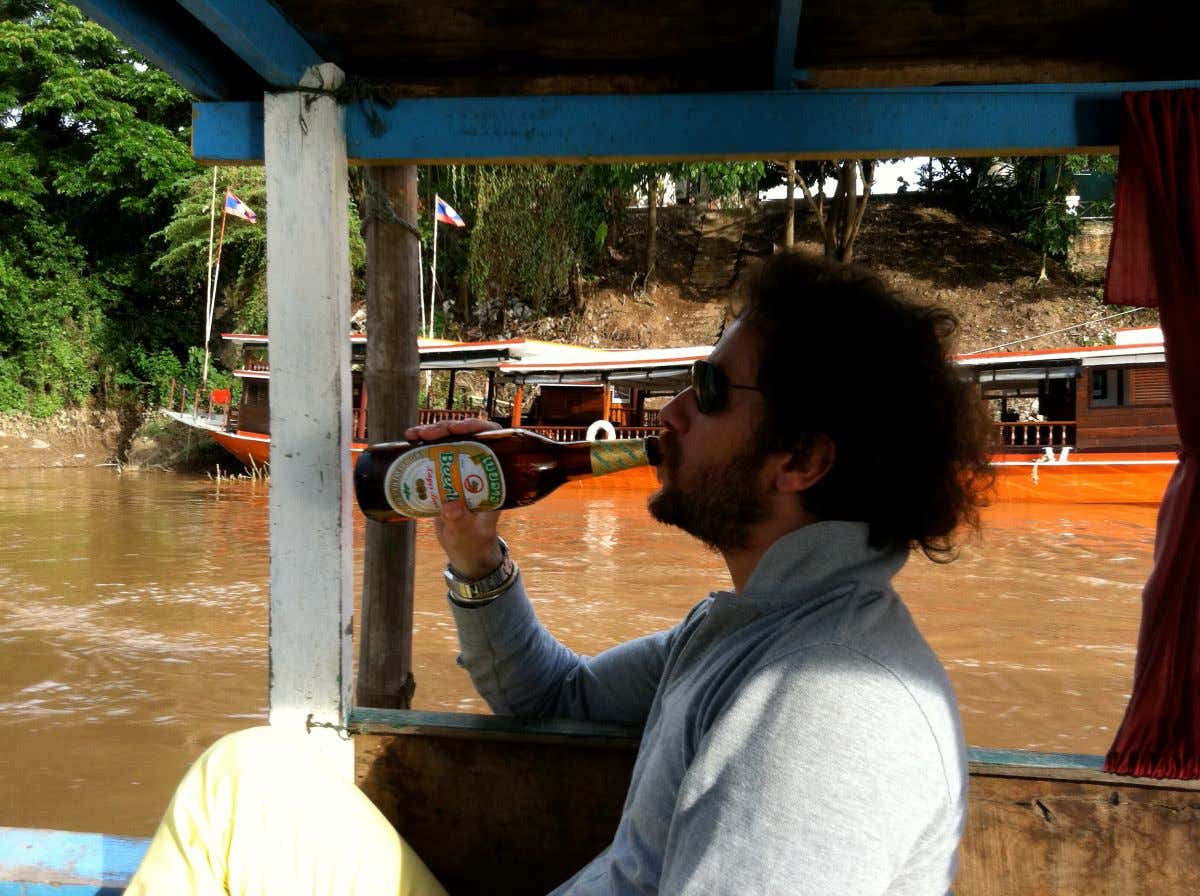 Francisco Calleja tomando una cerveza a bordo de una barca en el río Mekong, Laos
