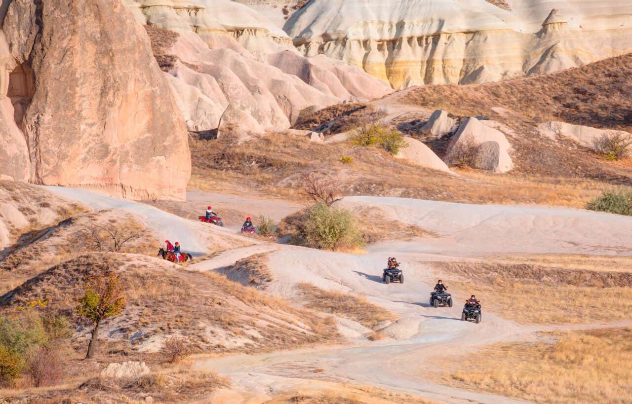 Panorâmica de um cenário da Capadócia com quadriciclos passando pelos caminhos