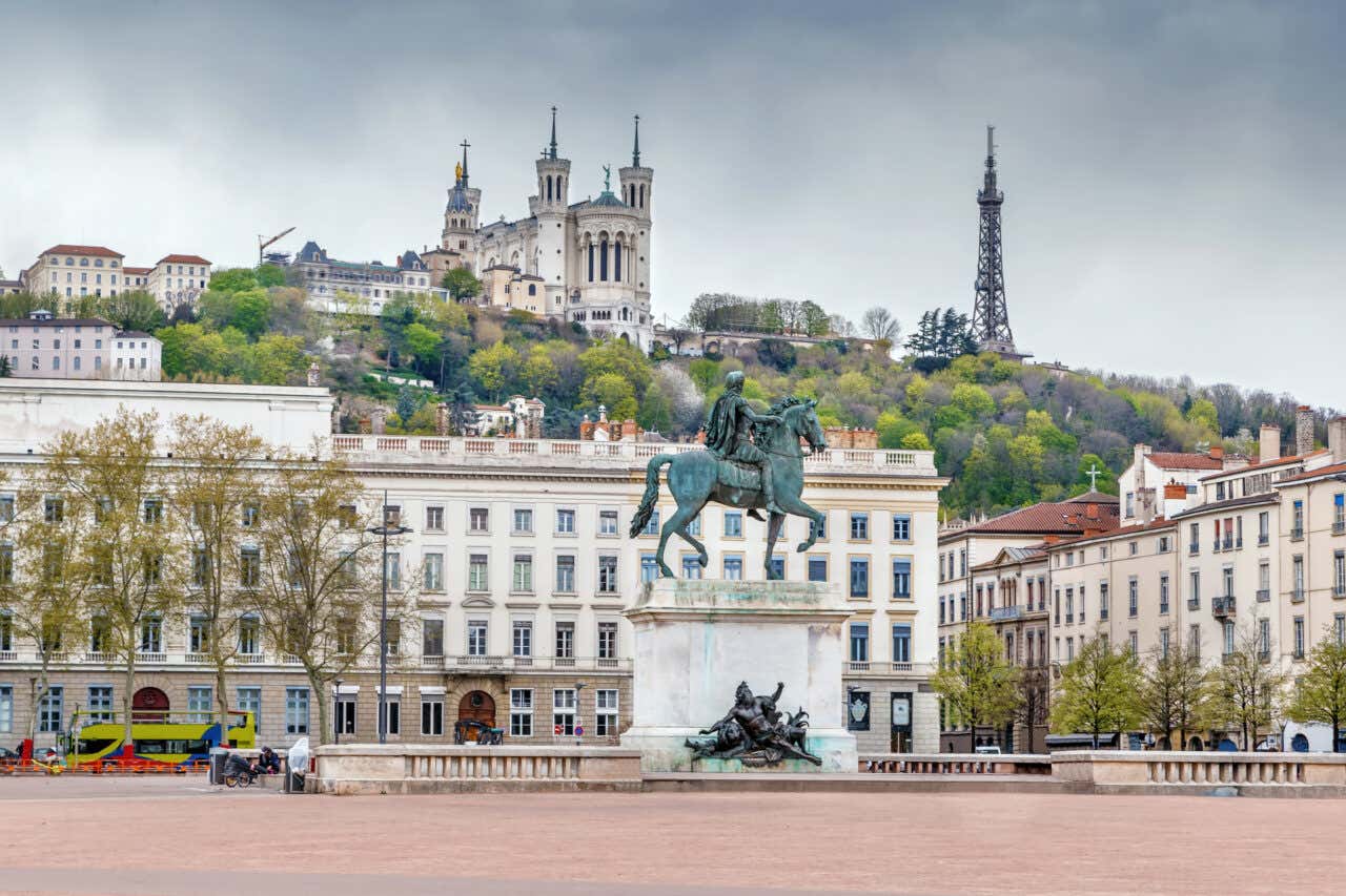 Place Bellecour avec une statue équestre au centre et la basilique de Fourvière la surplombant en arrière-plan