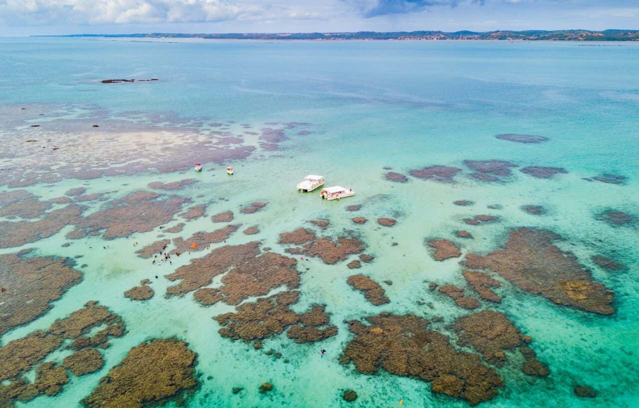 Vista aérea de barcos no mar transparente de Maragogi