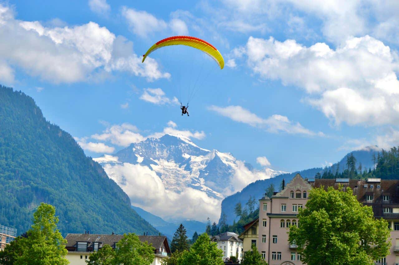 A paraglider in Interlaaken coming in the direction of the camera with a cloudy sky in the background and mountains.