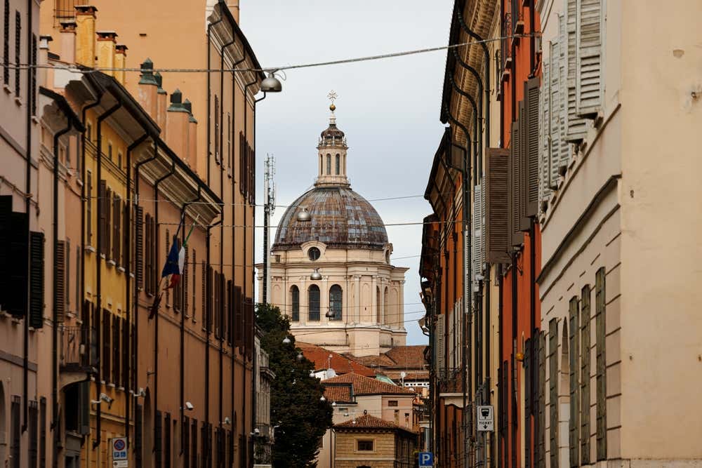 Vista della cupola di una chiesa in fondo a una strada del centro storico di Mantova