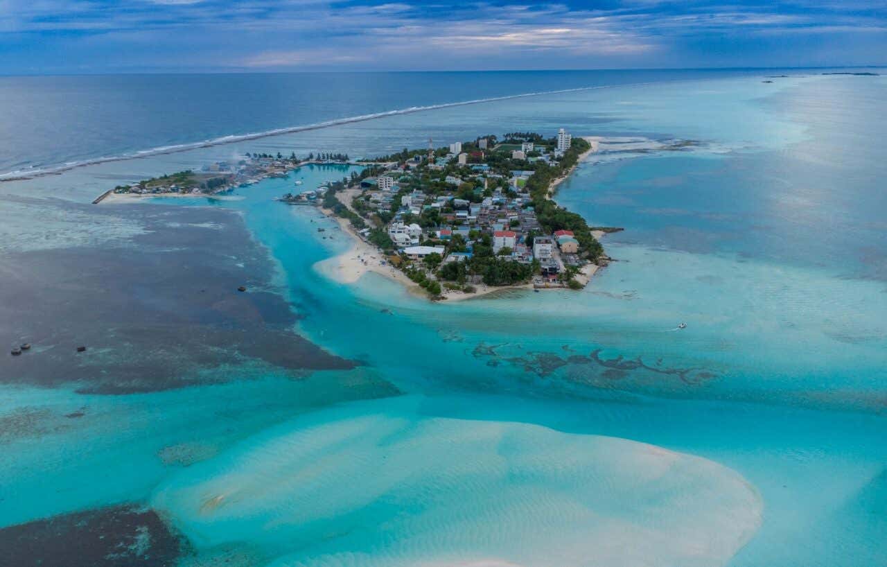 A luz dourada do sol dança na areia branca e fina, enquanto ondas suaves chegam à costa de Dhiffushi