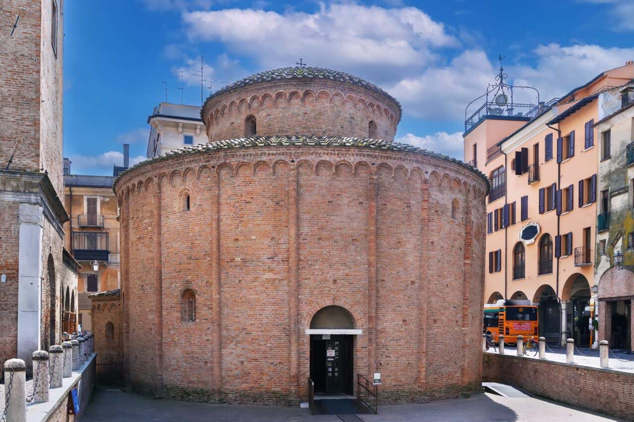 Antica chiesa romanica a pianta circolare dell'XI secolo con facciata in mattoni, cupola e colonnato esterni e una piccola porta di accesso che si apre sotto il livello della strada moderna