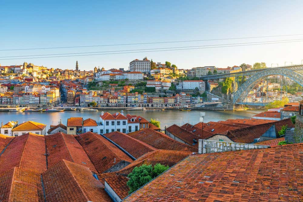 Vista panoramica del quartiere Ribeira della città di Porto con tetti rossi, fiume Douro e ponte Dom Luis all'alba,