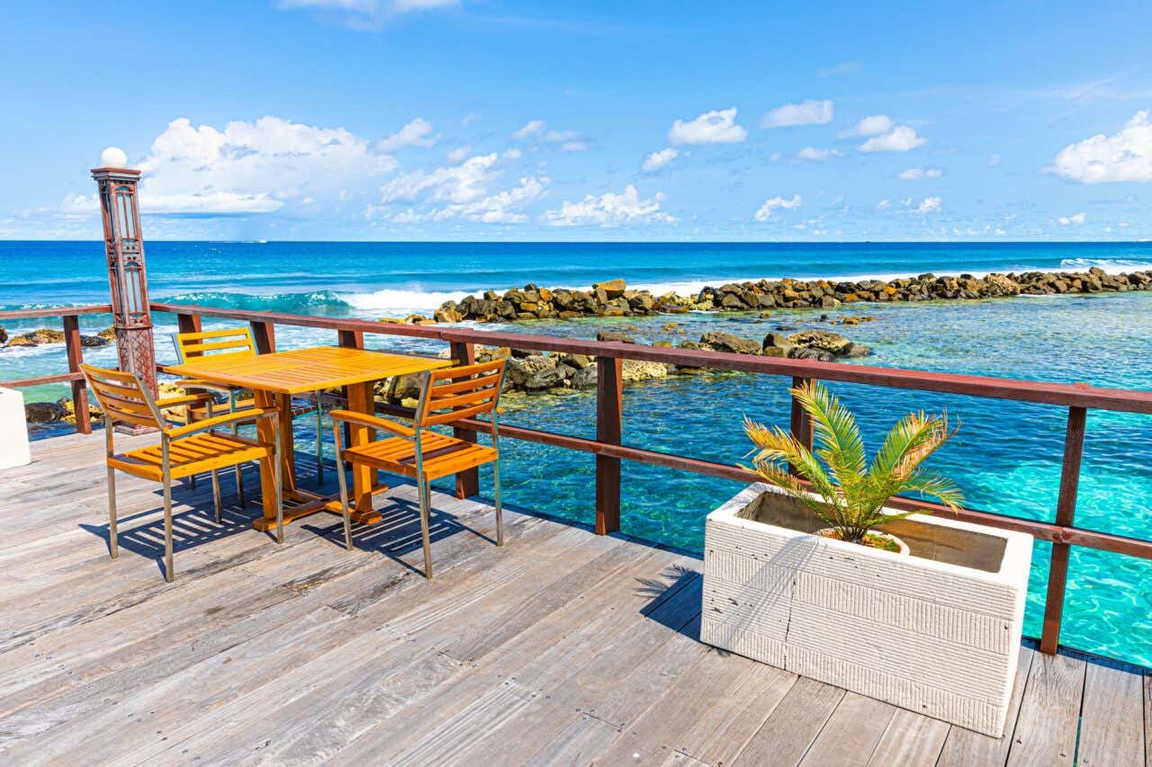 Mesa em um deck de madeira à beira-mar com rochas na água turquesa