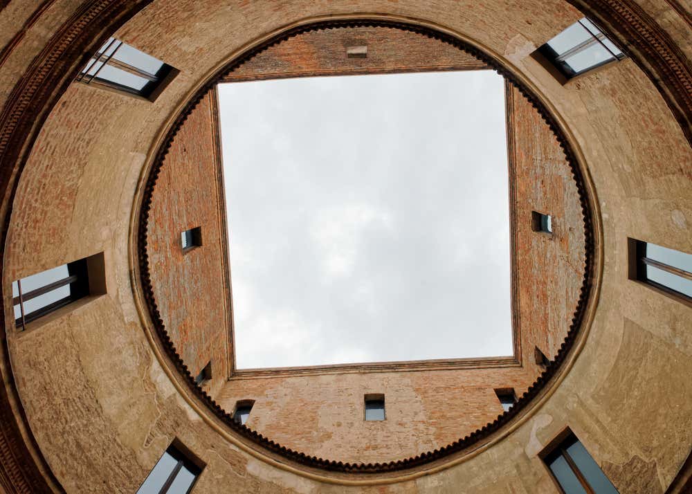 Veduta dal basso del cortile circolare della Casa del Mantegna a Mantova, con il cielo visibile attraverso l’apertura quadrata al centro