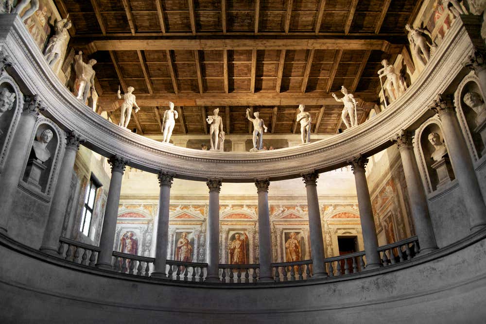 Interno del Teatro all’Antica di Sabbioneta, con la semicircolare fila di colonne, statue classiche sulla balaustra superiore e soffitto ligneo a cassettoni