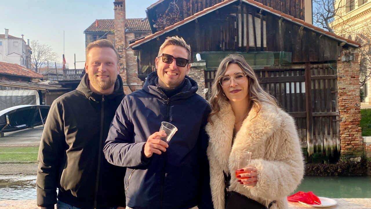 Due ragazzi e una ragazza con in mano un bicchiere di spritz in posa per una foto a Venezia durante il tour dei bacari