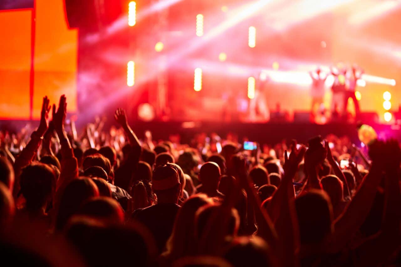 Pessoas olhando para o palco e desfrutando de um festival de música à noite