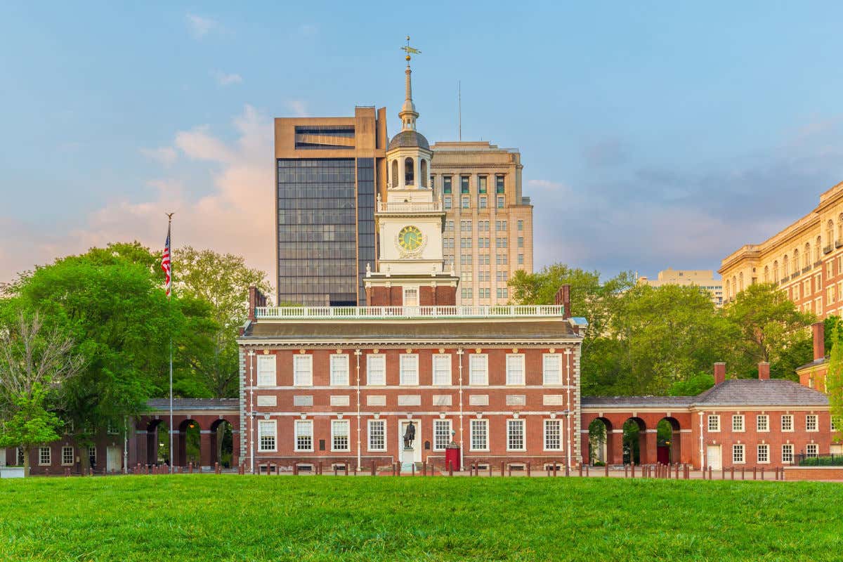 Un edificio de ladrillo y con una gran torre de reloj frente a un parque de Filadelfia