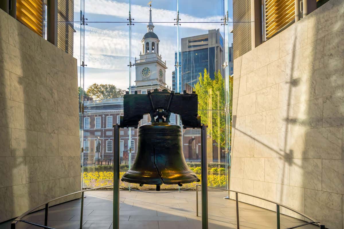 La Campana de la Libertad o Liberty Bell frente a un edificio histórico con una torre del reloj