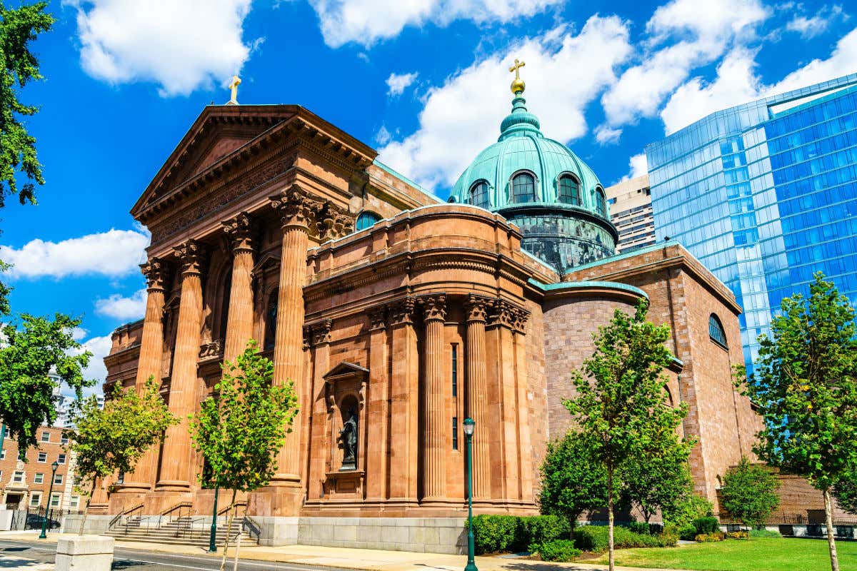 Fachada de la catedral basílica de San Pedro y San Pablo con de un color arenisco frente a varios edificios modernos