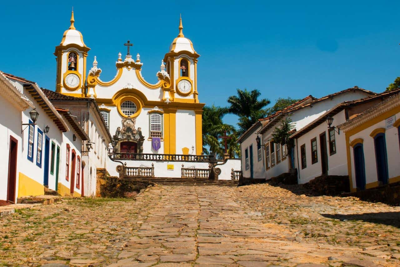 Vista da igreja Matriz de Santo Antônio, o templo católico mais antigo e principal de Tiradentes no cume da rua de pedras cercada de casas coloniais