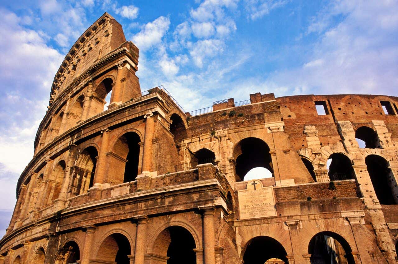 The Colosseum in Rome seen from below with a cloudy sky in the background.