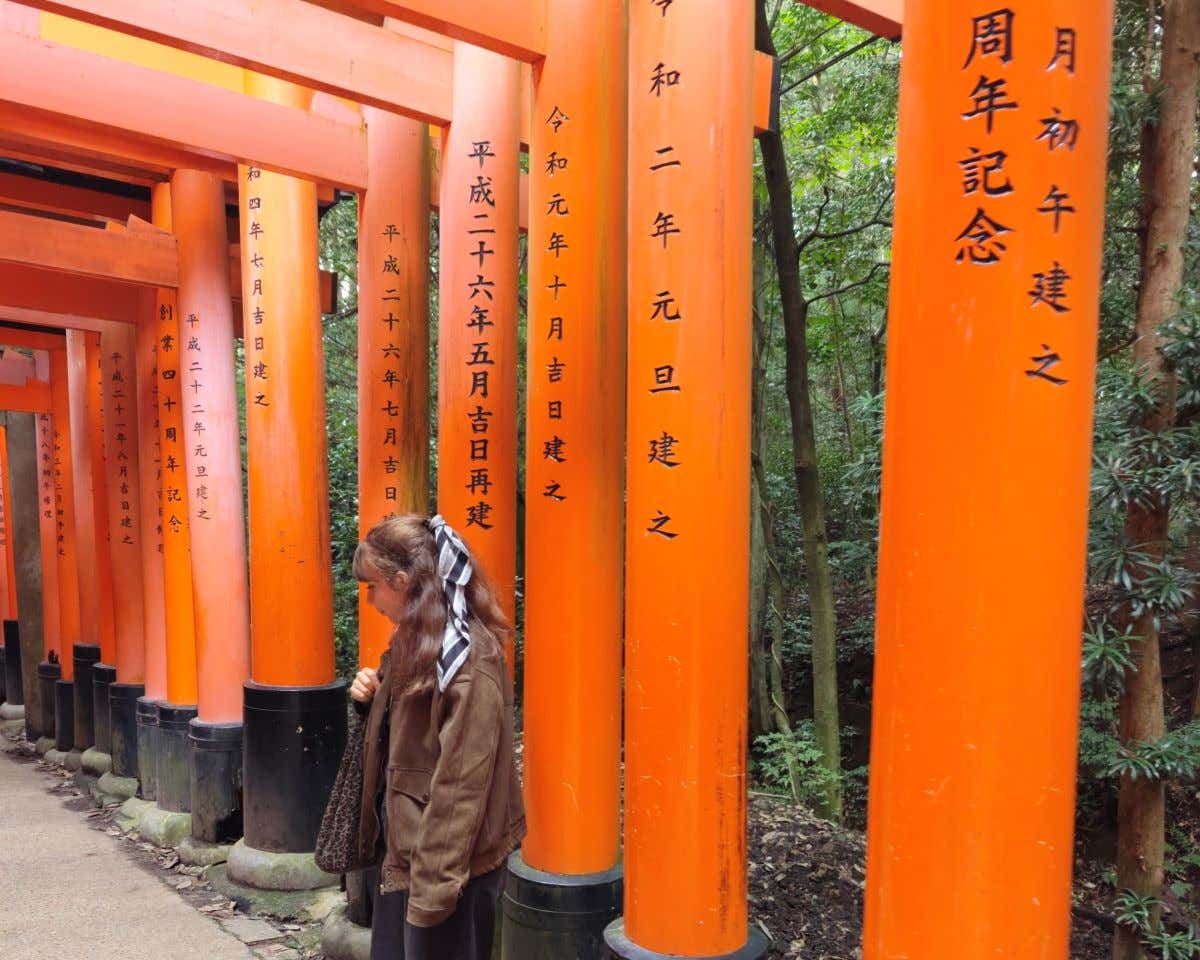 Chica posando con unos torii color anaranjado en el templo Fushimi Inari-Taisha