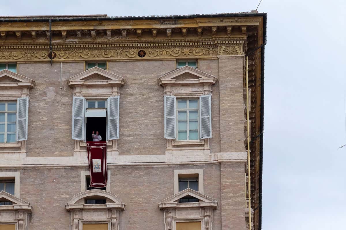 El Papa en la lejanía saludando a sus fieles desde una ventana de un palacio de fachada sobria
