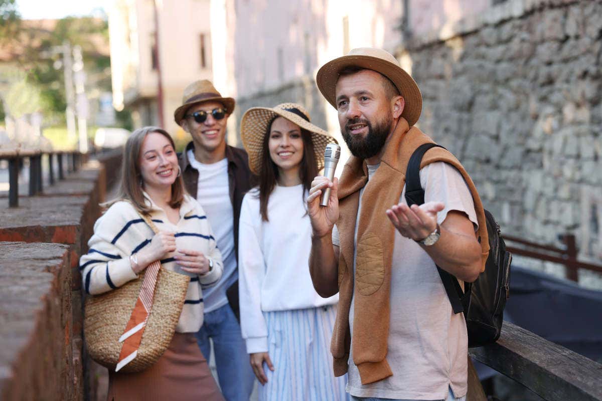 Un grupo de tres turistas junto a un guía con micrófono