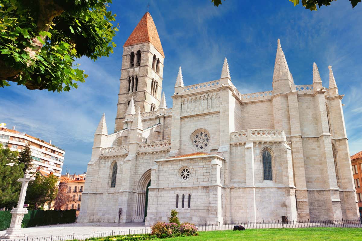 Exterior de una iglesia gótica con un campanario románico al fondo