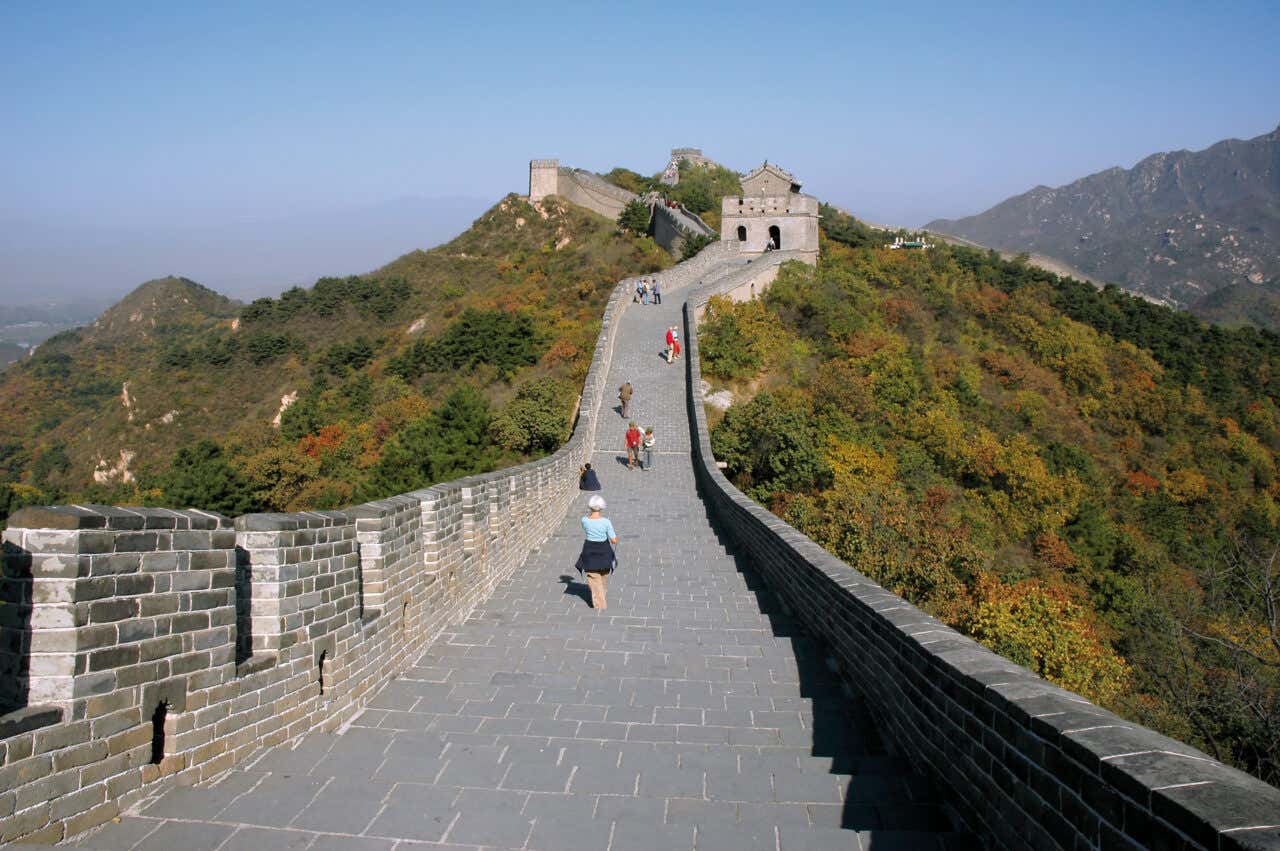 Section of the Great Wall of China in autumn with a few tourists walking along it
