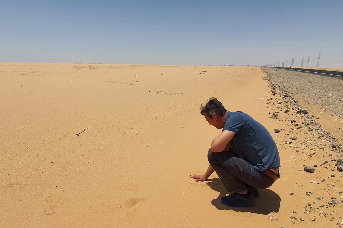 Un hombre tocando la arena del desierto de Egipto.