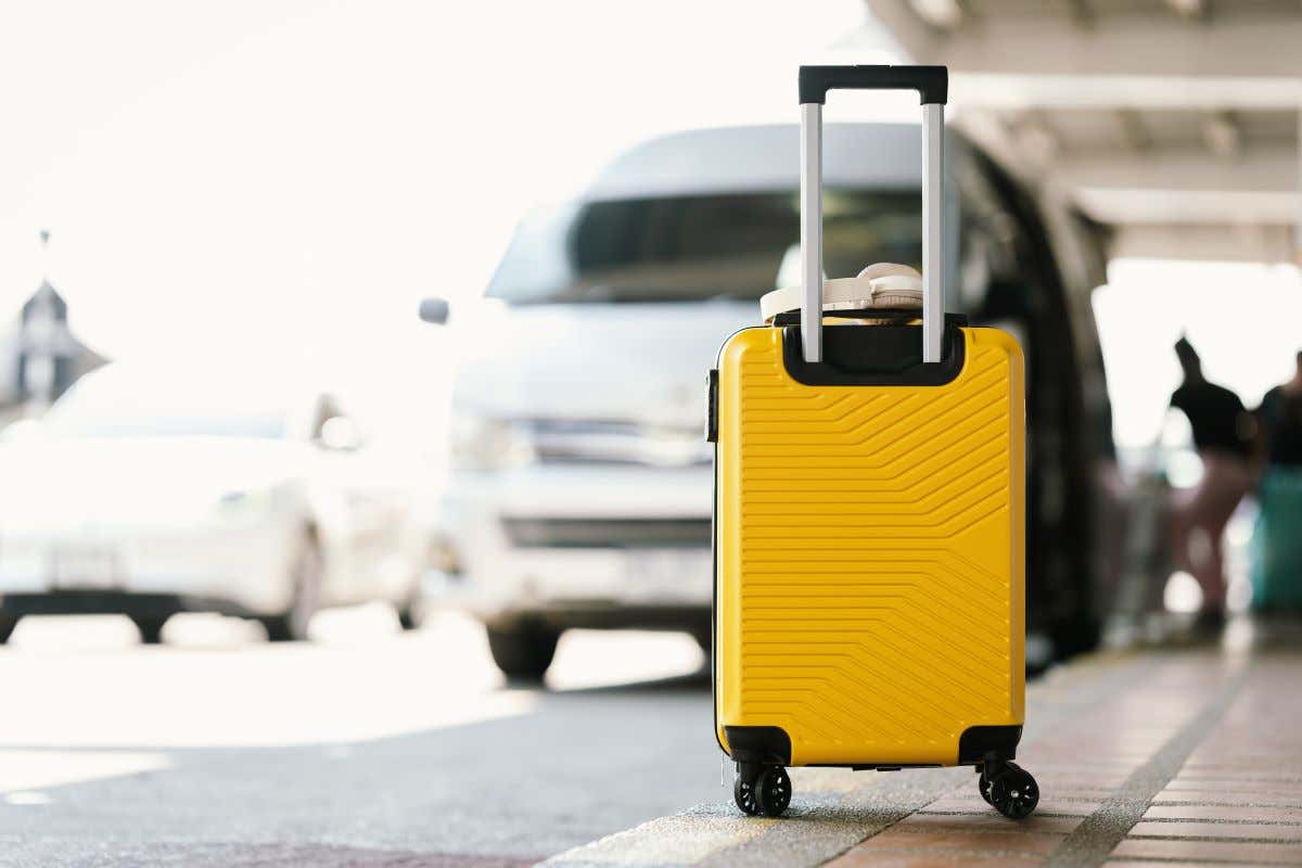 Detalle de una maleta amarilla junto a una furgoneta