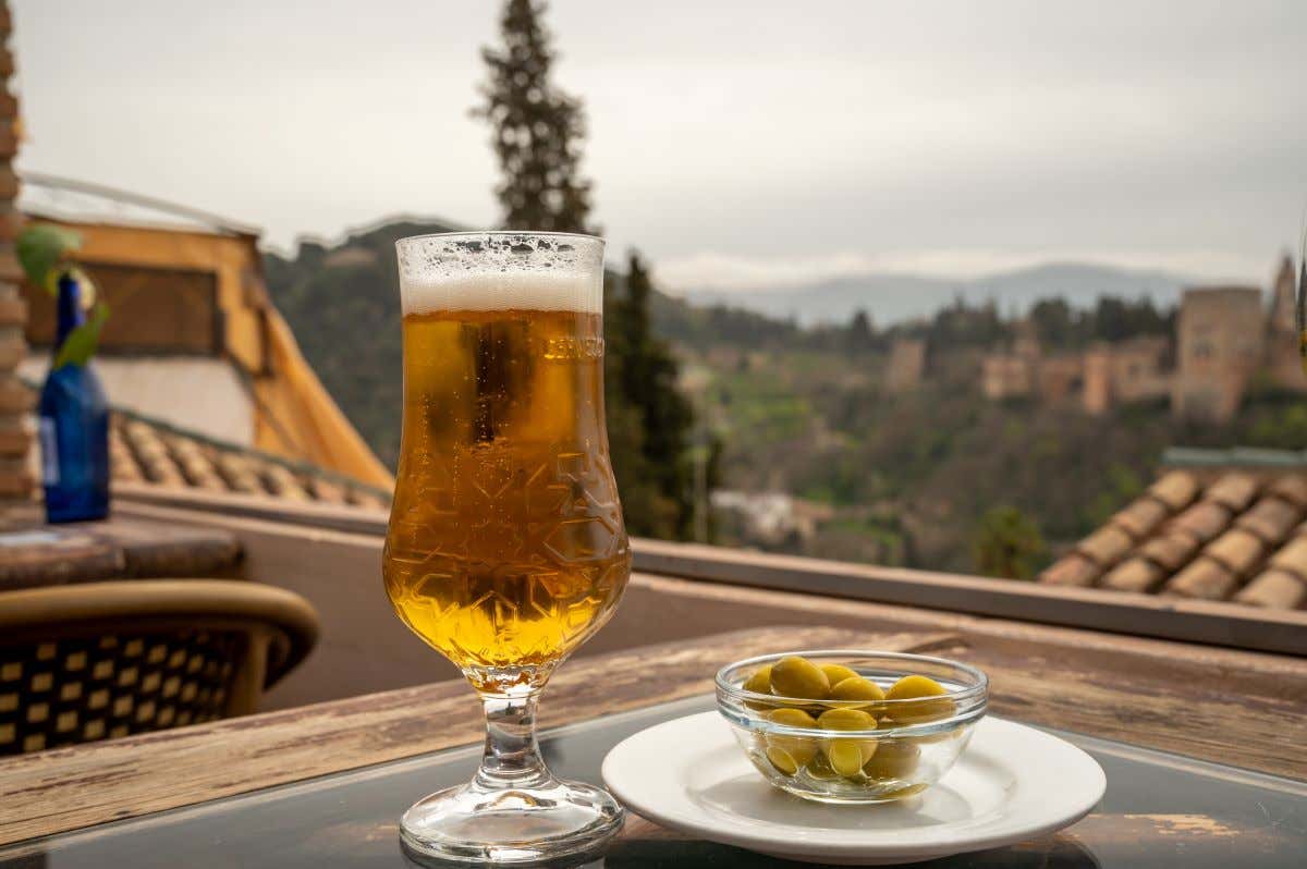 Vista detalle de una cerveza y una tapa de aceitunas desde un mirador de Granada