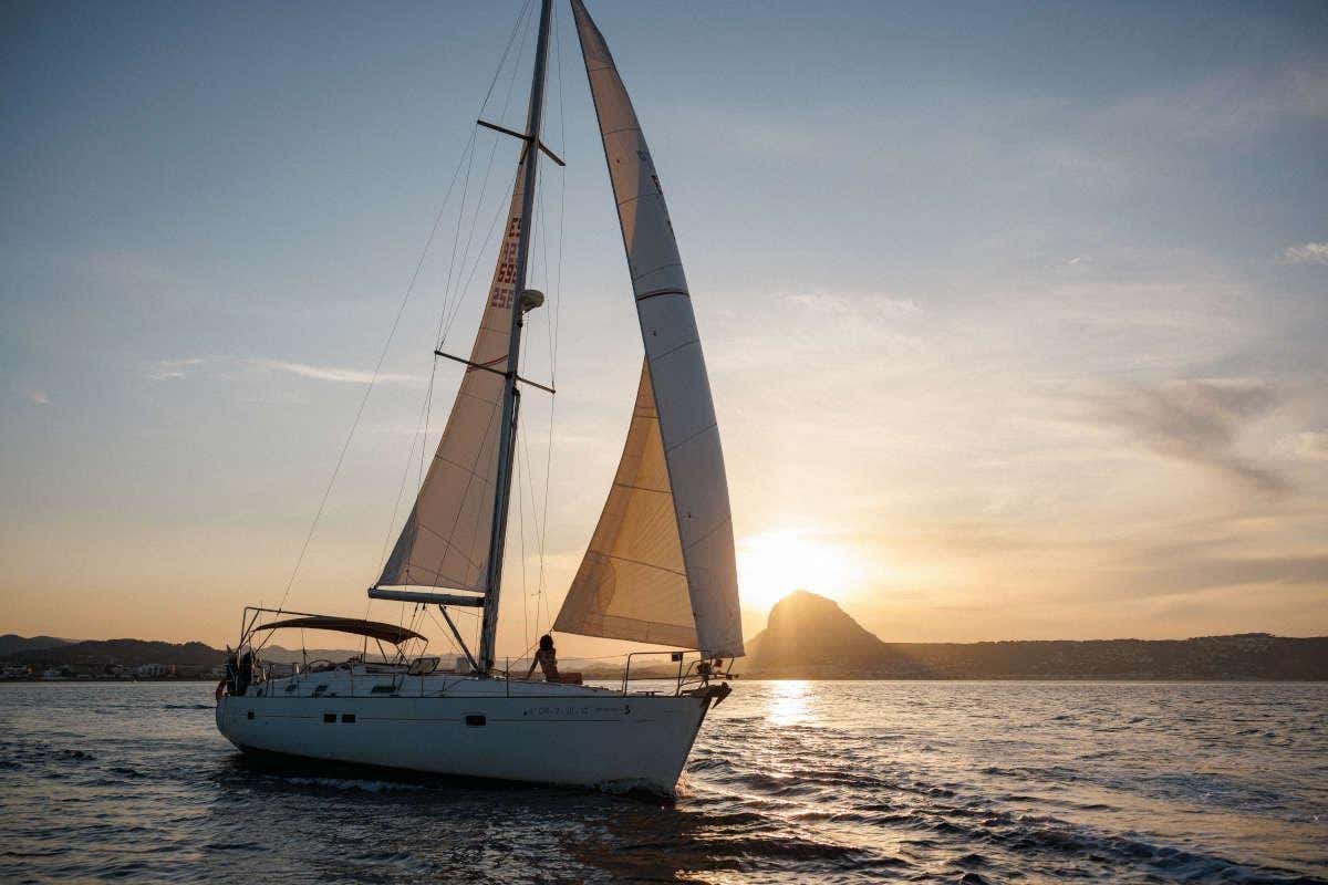 Un velero blanco navegando por el Mediterráneo al atardecer