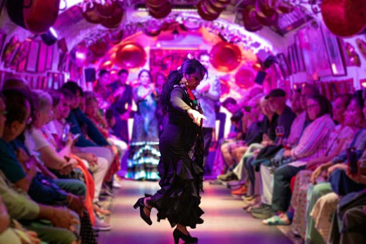 Interior de una cueva del Sacromonte donde se ve a gente contemplando a una bailaora de flamenco