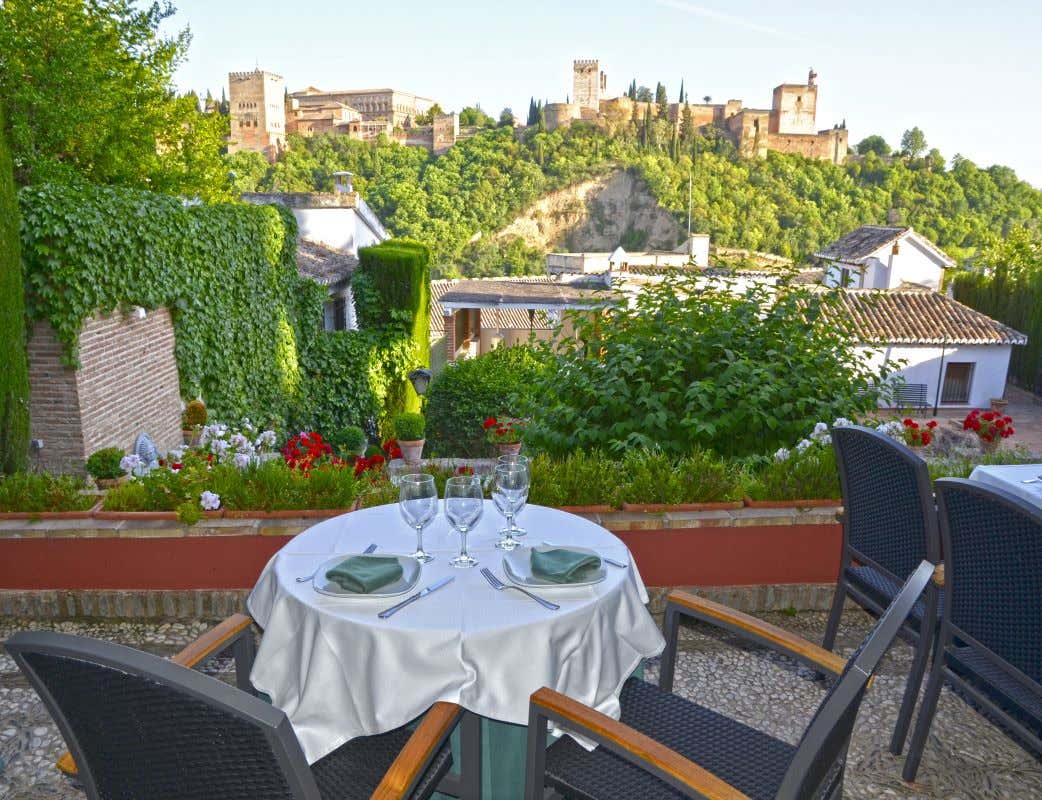 Una mesa de un restaurante con la Alhambra de fondo