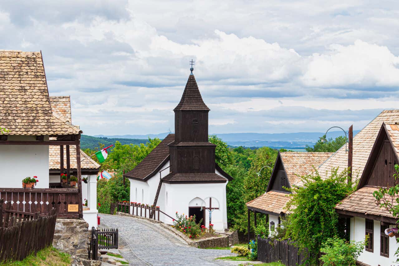 Traditional buildings and a quiet cobblestone street in Hollókő, Hungary on a cloudy day.